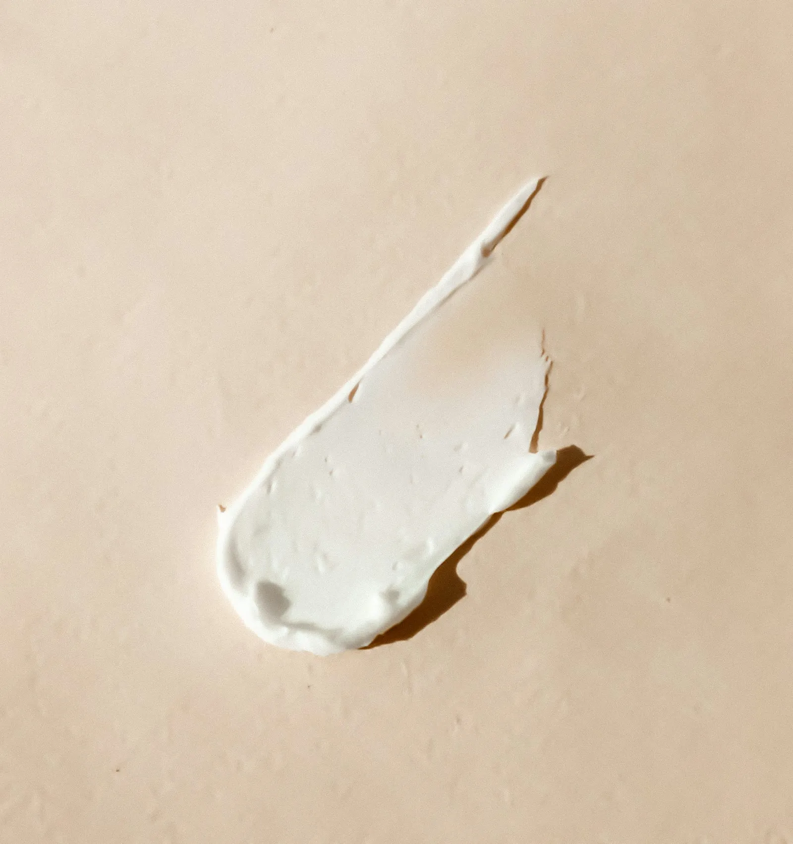 A smear of white cream on a warm beige surface